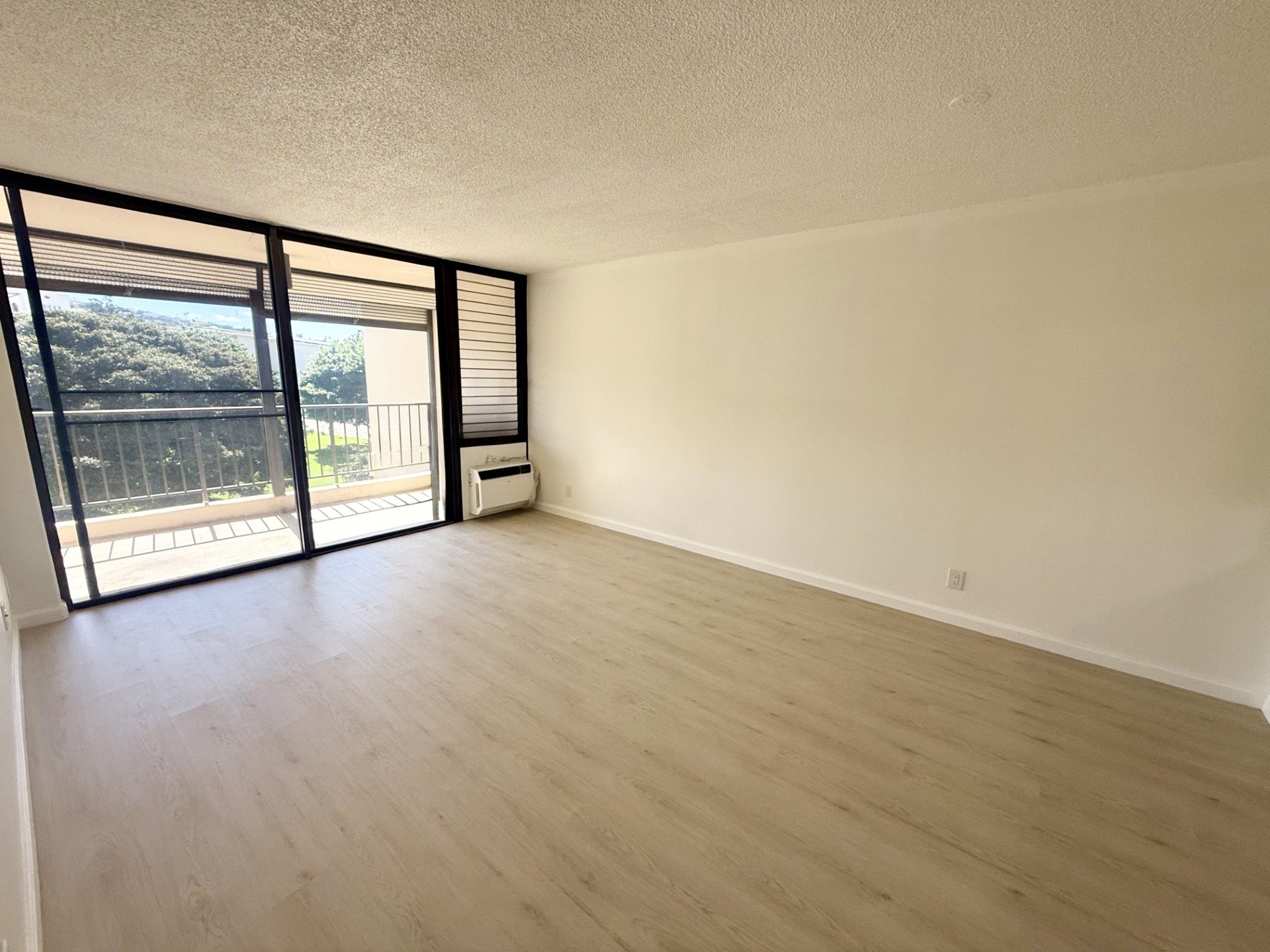 A room with a sliding glass door leading to a balcony.
